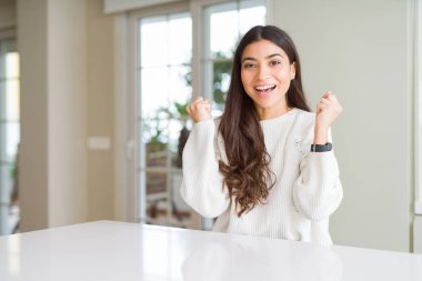 Beyaz masada evde genç güzel kadın şaşırttı ve silah yükseltilmiş ve açık gözleri ile başarı için hayran kutluyor. Kazanan kavramı.