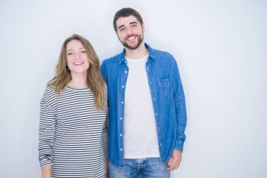 Genç güzel çift yüzünde mutlu ve serin bir gülümseme ile beyaz izole arka plan üzerinde birlikte duruyor. Şanslı kişi.