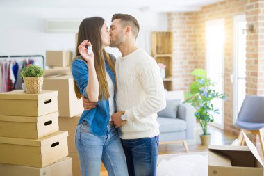 Genç çift yeni bir eve hareket, yeni dairenin anahtarlarını gösteren aşk sarılmak çok mutlu gülümseyen