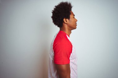 Afro saçlı Afro-Amerikan adam izole beyaz arka plan üzerinde kırmızı çizgili t-shirt giyen yan bakıyor, kendine güvenen gülümseme ile doğal yüzü ile profil poz dinlenmek.