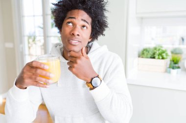 Afro-Amerikan adam tutan ve portakal suyu ciddi yüz soru, çok karışık fikir düşünme cam içme