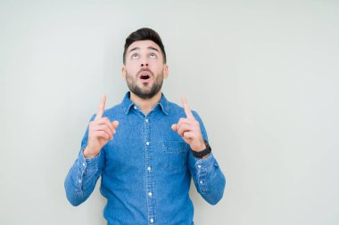 Yakışıklı delikanlı izole arka plan üzerinden hayran ve yukarıya bakıp parmakları ile işaret şaşırttı ve silah kaldırdı.