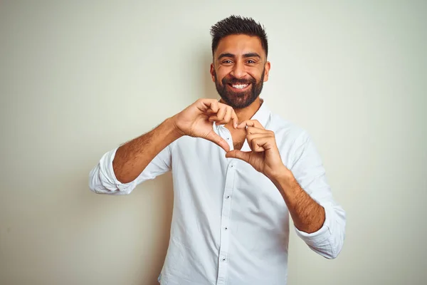 孤立した白い背景の上に立つエレガントなシャツを着た若いインド人男性は 心のシンボルと形を手で示す愛に微笑んでいます ロマンチックなコンセプト — ストック写真