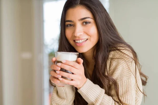 Hermosa joven bebiendo una taza de café en casa y sonriendo —  Fotos de Stock