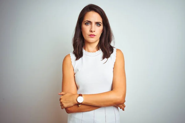 Young beautiful woman wearing dress standing over white isolated background skeptic and nervous, disapproving expression on face with crossed arms. Negative person.