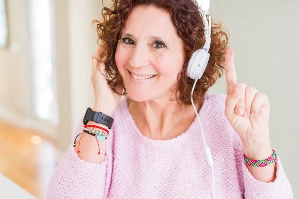 幸せそうな顔で指を指すアイデアや質問に驚いた音楽を聴いてヘッドフォンを着用したシニア女性 ナンバーワン — ストック写真