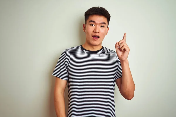 年轻的亚洲中国男子穿着条纹T恤站在孤立的白色背景上 指着手指 成功的想法 退出和快乐 — 图库照片