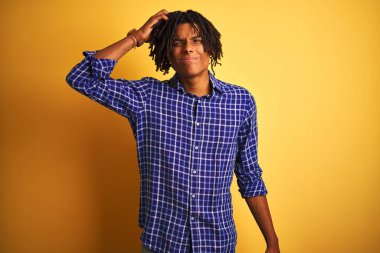 Izole sarı arka plan üzerinde duran rahat gömlek giyen dreadlocks ile Afro adam karıştırmayın ve soru hakkında merak ediyorum. Şüpheyle belirsiz, eliyle kafada düşünmek. Pensive kavramı.