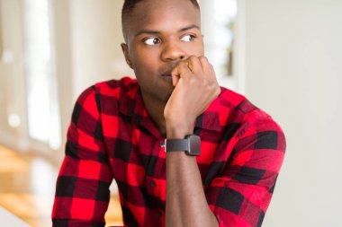 Yakışıklı afro-amerikan adam stresli ve sinirli ağız tırnakısırma elleri ile bakıyor. Anksiyete sorunu.