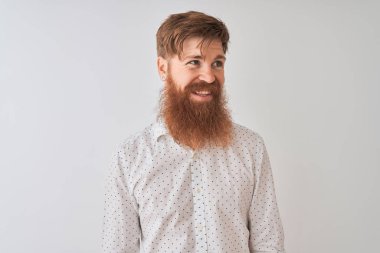 Genç kızıl saçlı İrlandalı adam izole beyaz arka plan üzerinde duran gömlek giyen yüzünde gülümseme, doğal ifade ile yan bakıyor. Gülmekten emin.