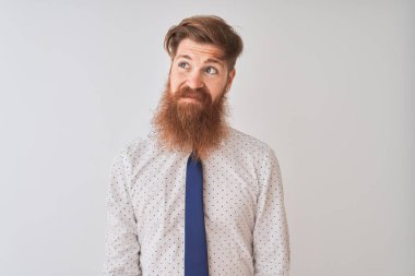 Genç kızıl saçlı İrlandalı işadamı izole beyaz arka plan üzerinde duran yan bakarak gülümseyerek ve düşünme uzak bakıyor.