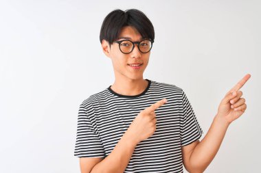 Çinli adam gözlük ve lacivert çizgili t-shirt izole beyaz arka plan üzerinde gülümseyerek ayakta giyen ve yan iki el ve parmakları ile işaret kamera bakıyor.