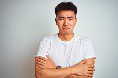 Genç Asyalı Çinli adam yüzünde üzgün ve şok ifade ile kış soğuk için sallayarak ve donma izole beyaz arka plan üzerinde duran t-shirt giyen