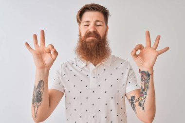 Genç kızıl İrlandalı adam izole beyaz arka plan üzerinde duran polo giyen dinlenmek ve gözleri parmakları ile meditasyon jest yapıyor kapalı gülümseyerek. Yoga konsepti.