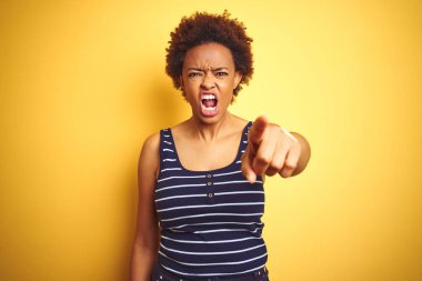 Beauitul afro-amerikan kadın izole sarı arka plan üzerinde yaz t-shirt giyen hoşnut olmayan işaret ve kameraya sinirli, kızgın ve öfkeli size