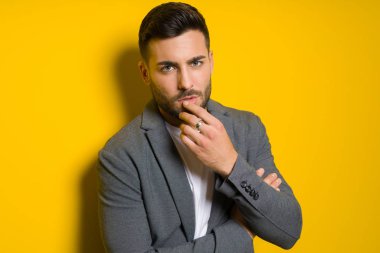 Genç yakışıklı adam possing ve modelleme sarı izole bac üzerinde