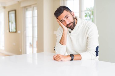 Yakışıklı İspanyol adam evde rahat beyaz kazak giyen yorgun görünümlü ve çapraz kolları ile depresyon sorunları ile sıkılmış düşünme.