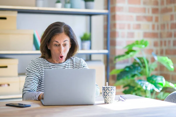 中年老妇人坐在桌旁工作 用电脑笔记本电脑吓得吓了一跳 吓得吓了一跳 害怕和兴奋的表情 — 图库照片