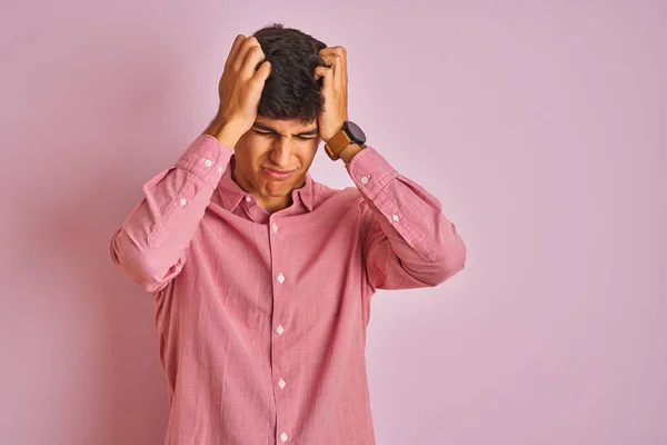 若いインド人男性は 痛みと偏頭痛のために絶望的な頭痛に苦しんで孤立したピンクの背景の上に立ってエレガントなシャツを着て 頭の上に手を置く — ストック写真