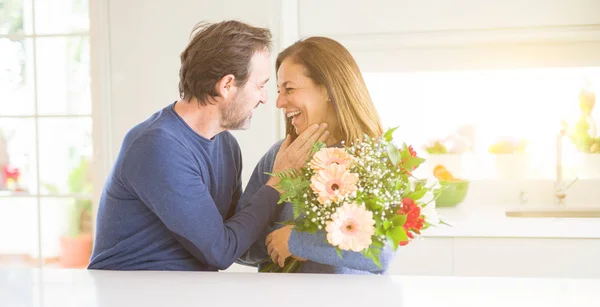 Romántica pareja de mediana edad sosteniendo flores enamoradas en casa — Foto de Stock