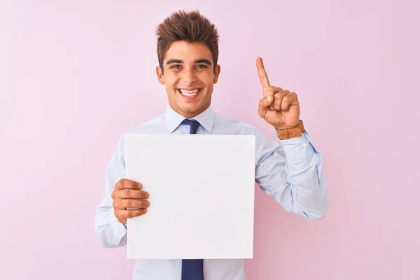 Jovem Empresário Bonito Segurando Banner Sobre Fundo Rosa Isolado Surpreso — Fotografia de Stock