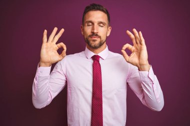Mor izole arka plan üzerinde zarif gömlek ve kravat giyen genç iş adamı dinlenmek ve parmakları ile meditasyon jest yapıyor kapalı gözleri ile gülümseyerek. Yoga konsepti.