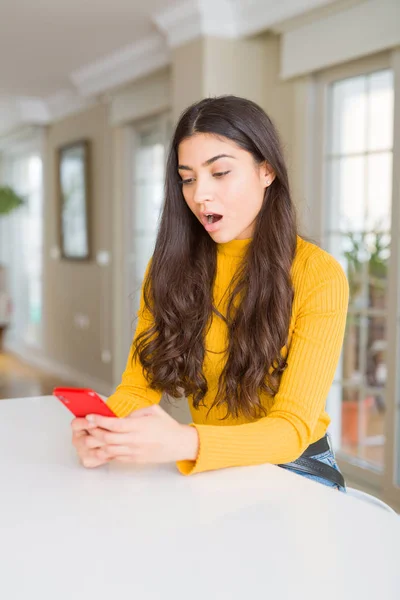 Młoda Kobieta Pomocą Czerwonego Smartfona Wysyłając Wiadomość Przestraszona Szoku Niespodzianką — Zdjęcie stockowe