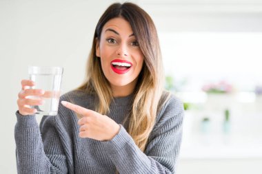 Genç güzel kadın evde su bardağı içme çok mutlu el ve parmak ile işaret