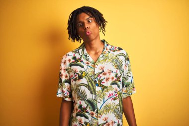 Tatilde dreadlocks ile Afro adam izole sarı arka plan üzerinde yaz gömlek giyen dudakları, çılgın ve komik jest ile balık yüz yapma. Komik ifade.