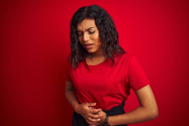 Güzel transseksüel transseksüel kadın mide üzerinde el ile izole kırmızı arka plan üzerinde t-shirt giyiyor çünkü hazımsızlık, ağrılı hastalık kötü hissediyorum. Ağrı kavramı.