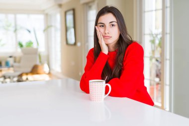 Güzel genç kadın bir fincan sade kahve düşünme seyir içme yorgun ve sıkılmış çapraz silah depresyon sorunları ile.