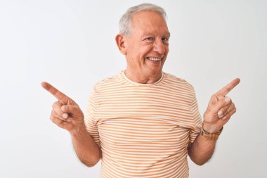 Üst düzey gri saçlı adam izole beyaz arka plan üzerinde duran çizgili t-shirt giyen farklı yönlere parmakları ile işaret emin gülümseyerek. Reklam için kopya alanı