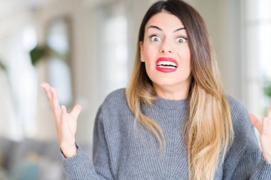 Evde çılgın ve kızgın bağırarak ve agresif ifade ve silah kaldırdı bağırmaya kış kazak giyen genç güzel kadın. Hayal kırıklığı kavramı.