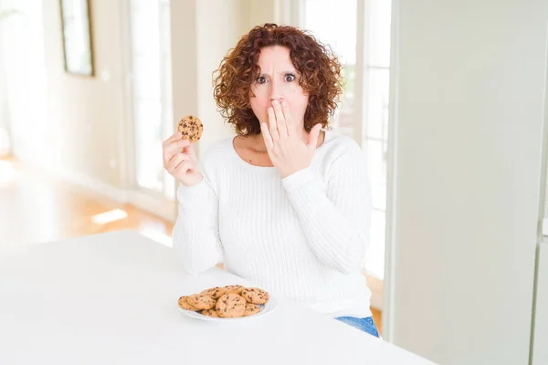 Mujer Mayor Comiendo Galletas Chispas Chocolate Casa Cubrir Boca Con —  Fotos de Stock