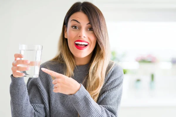 Genç güzel kadın evde su bardağı içme çok mutlu el ve parmak ile işaret