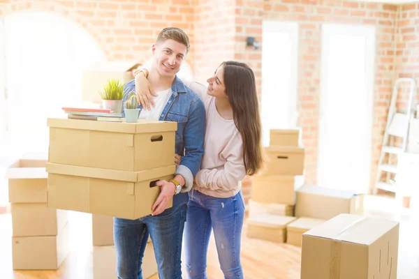 Belo jovem casal sorrindo no amor segurando caixas de papelão — Fotografia de Stock