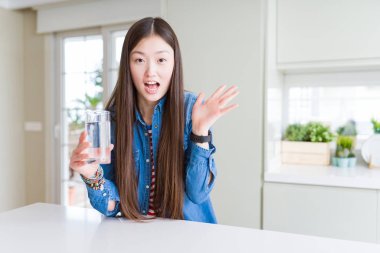 Güzel Asyalı kadın çok mutlu ve heyecanlı tatlı su bir bardak içme, kazanan ifade büyük bir gülümseme ile çığlık zafer kutluyor ve ellerini kaldırdı