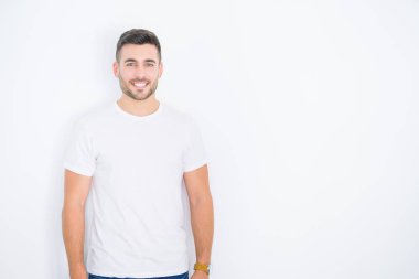 Beyaz izole arka plan üzerinde rahat beyaz t-shirt giyen mutlu gülümseyen genç yakışıklı adam