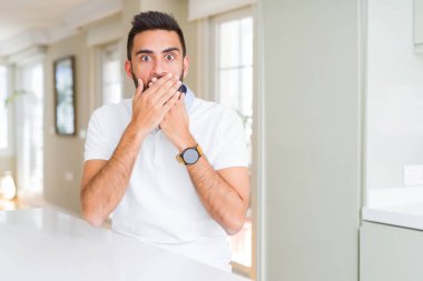 İspanyol yakışıklı casual beyaz t-shirt evde ağız hata için elleriyle kapsayan şok. Gizli kavramı.