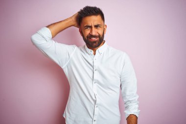 İzole edilmiş pembe arka planın üzerinde duran zarif gömlek giyen hintli işadamı kafalarını karıştırıyor ve merak ediyor. Şüpheyle belirsiz, eliyle kafada düşünmek. Pensive kavramı.