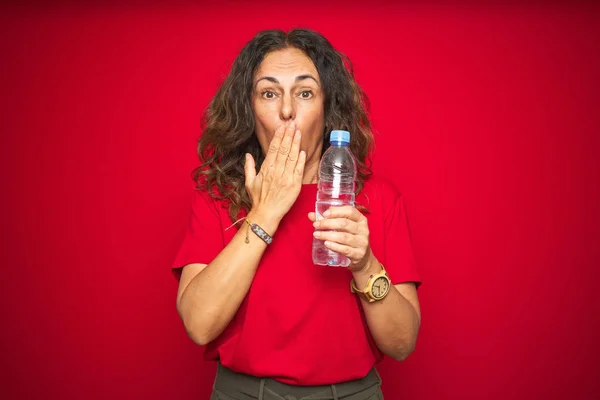 Seniorin Mittleren Alters Mit Plastikwasserflasche Über Rotem Isoliertem Hintergrunddeckel Mund — Stockfoto