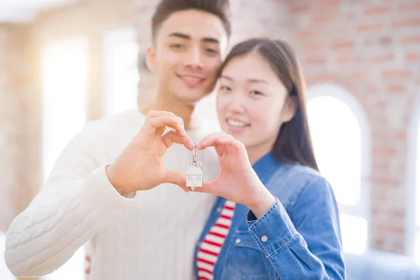 Young asian couple holding keys of new house, smiling happy and excited moving to a new apartment