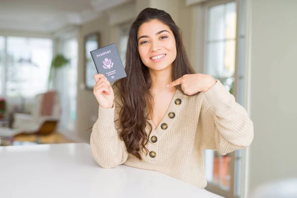 Young woman holding passport of United States of America with surprise face pointing finger to himself