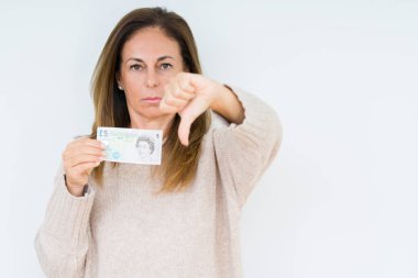 Orta yaş kadın kızgın yüz ile izole arka plan üzerinde 5 lira banka notu tutan, başparmak aşağı, ret kavramı ile sevmediğimi gösteren negatif işareti