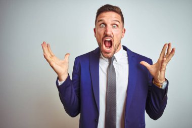 Beyaz izole arka plan üzerinde genç yakışıklı iş adamı deli kutluyor ve kollarını kaldırdı ve açık gözleri heyecanlı çığlık ile başarı için hayran. Kazanan kavramı