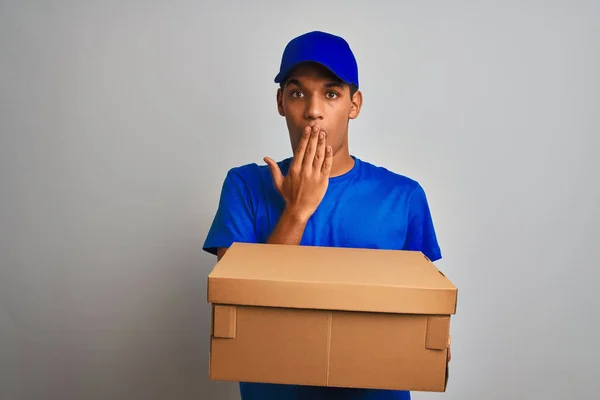 Young handsome arab delivery man holding a box standing over isolated white background cover mouth with hand shocked with shame for mistake, expression of fear, scared in silence, secret concept