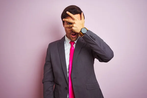 양복과 넥타이를 고립된 분홍색 서있는 잘생긴 사업가는 얼굴과 손으로 부끄러운 — 스톡 사진