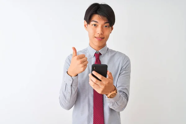 中国商人打着领带 用智能手机站在孤立的白色背景上高兴 大微笑做Ok标志 竖起大拇指用手指 优秀的标志 — 图库照片