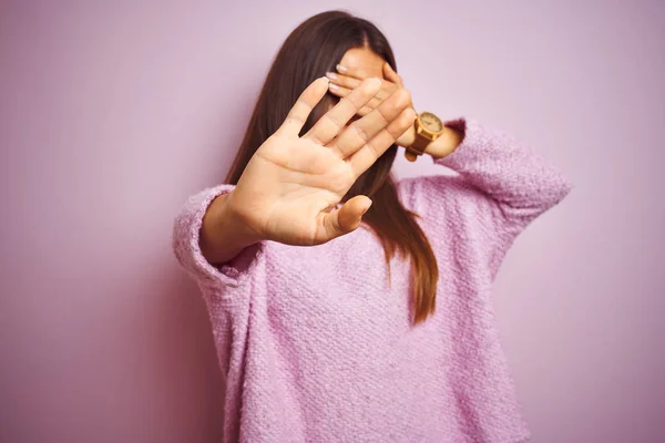 カジュアルなセーターを着た若い美しい女性は 孤立したピンクの背景の上に立って 手で目を覆い 悲しみと恐怖の表情でストップジェスチャーを行います 恥ずかしいと否定的な概念 — ストック写真