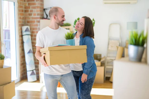 Jong paar verhuizen naar een nieuw huis, glimlachend gelukkig houden cardboa — Stockfoto